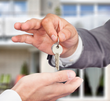 Property Agent Giving Keys To Owner Against New House