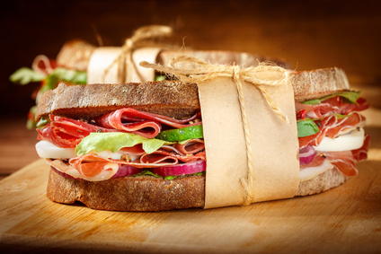 Sandwich with bacon and fresh vegetables on vintage wooden cutting board. Close-up.