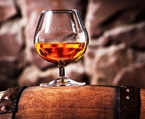 Glass of cognac on the old wooden barrel